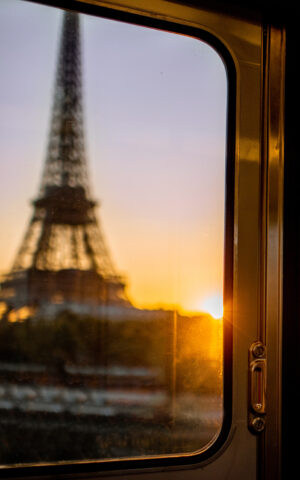 Une femme dans une rame de métro, avec la Tour Eiffel visible à travers la fenêtre.