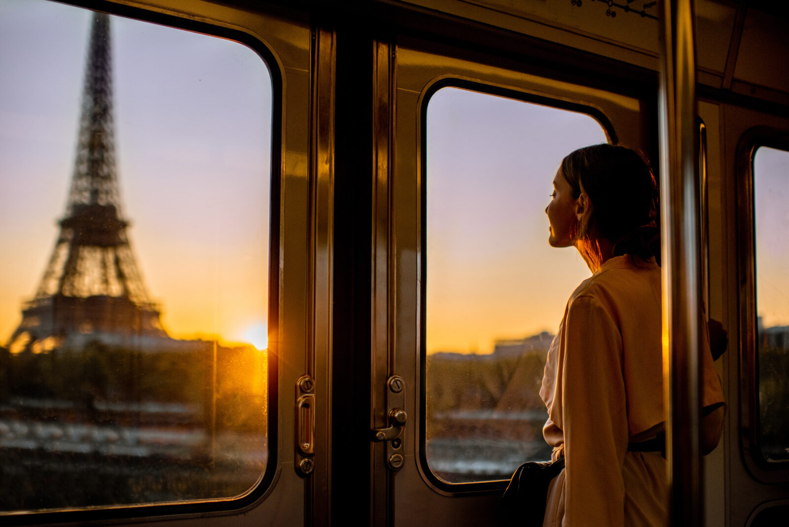 Une femme dans une rame de métro, avec la Tour Eiffel visible à travers la fenêtre.