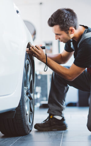 Une personne vérifie la pression des pneus d'une voiture à l'aide d'un manomètre.