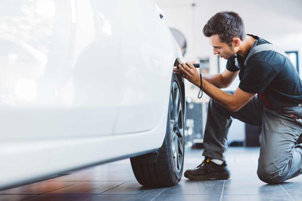 Une personne vérifie la pression des pneus d'une voiture à l'aide d'un manomètre.