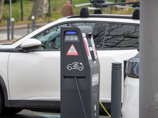 Voiture électrique branchée sur une borne de recharge avec un Disque vert sur le pare-brise