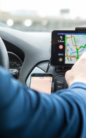 Un homme est assis dans sa voiture, utilisant le GPS pour se rendre au travail, illustrant la mobilité professionnelle quotidienne.