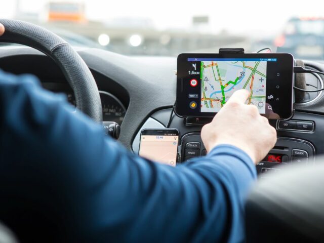 Un homme est assis dans sa voiture, utilisant le GPS pour se rendre au travail, illustrant la mobilité professionnelle quotidienne.