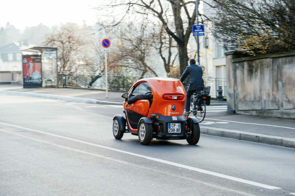 Une voiture électrique circulant en milieu urbain, représentant une solution de mobilité écologique et économique pour les entreprises.