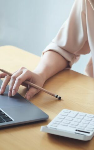 Une femme est assise à son bureau, entourée de documents et son ordinateur, illustrant la réussite de la gestion du Total Cost of Mobility (TCM) dans l'entreprise. Cette image symbolise l'efficacité de l'optimisation financière et la performance de la mobilité professionnelle.