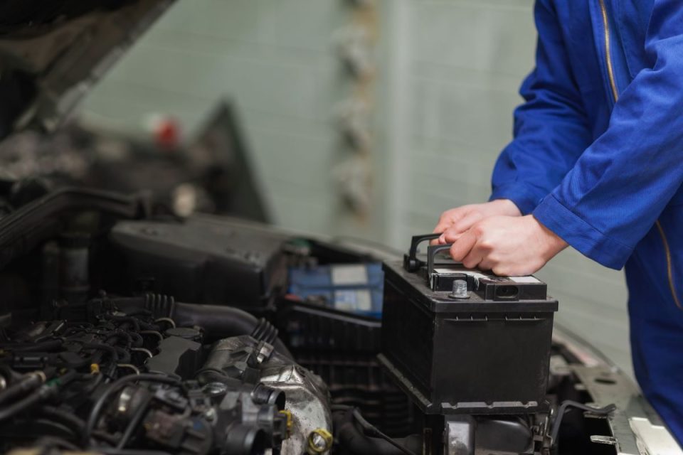 Garagiste qui met en place une batterie dans un voiture électrique.