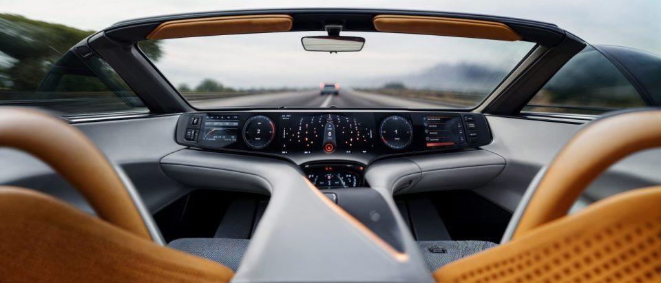 Vue intérieure d’une voiture futuriste entièrement autonome, sans volant, avec un tableau de bord high-tech affichant une interface numérique avancée.