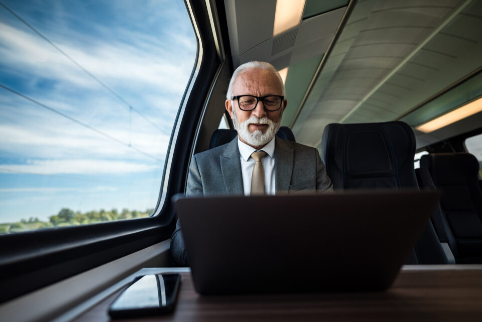 Un homme travaillant sur son ordinateur portable dans un train, illustrant la flexibilité professionnelle offerte par la Loi d'Orientation des Mobilités (LOM).