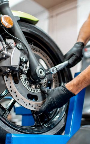 Un mécanicien professionnel inspecte minutieusement un deux-roues dans un centre de contrôle technique agréé.